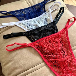May include: Four pairs of lacy underwear in red, black, white, and blue. The underwear is made of delicate lace and has a feminine design.