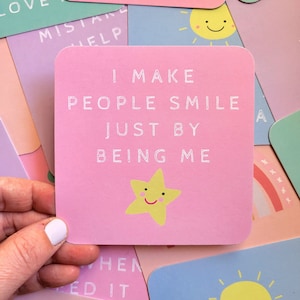 Op de afbeelding: Roze kaart met een affirmatie met een gele ster en de tekst "Ik maak mensen blij door gewoon mezelf te zijn."
