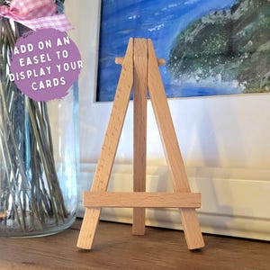 May include: A small wooden easel, perfect for displaying cards or small artwork. The easel is made of natural wood and has a simple, classic design.