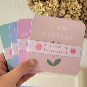 May include: A set of four pink, purple, blue, and green cards with the text "I AM SPECIAL" and "Kids Cards of Encouragement" on the front. The cards have a floral design with pink and purple flowers.