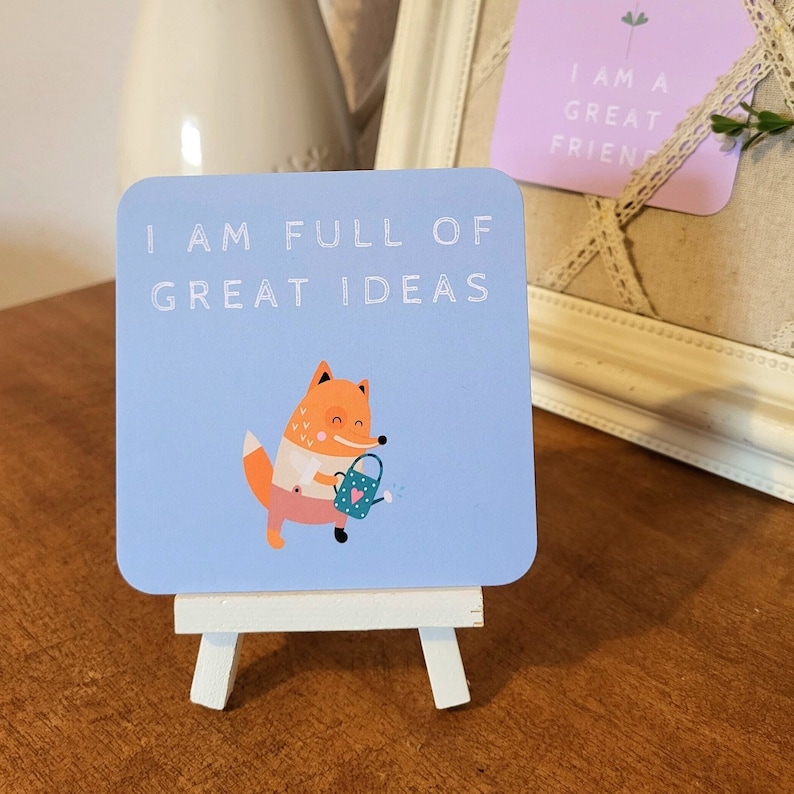 May include: A blue card with a fox holding a watering can and the text "I am full of great ideas". The card is on a small white easel.