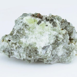 May include: A raw mineral specimen featuring a cluster of pale green and translucent crystals embedded within a rough, greyish-white matrix. The stone displays varied textures with sparkling crystalline facets and opaque mineral deposits across its surface.