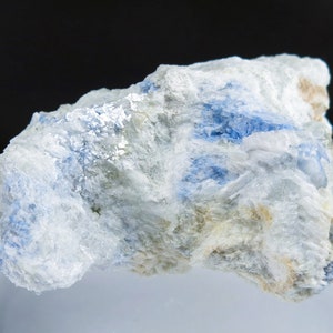 May include: A rough, white rock with blue streaks of mineral. The rock has a rough, uneven texture.