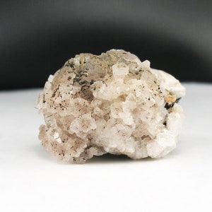 May include: A cluster of small, white and grey crystals with a rough, natural texture.