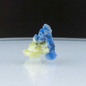 May include: A small, blue and yellow mineral specimen. The mineral has a rough, crystalline texture.