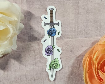 Könnte beinhalten: Ein Aufkleber mit einem silbernen Schwert, auf dem drei Rosen sind. Die Rosen sind blau, lila und grün.