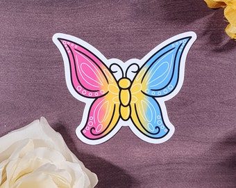 Könnte beinhalten: Ein Aufkleber mit einem Schmetterling mit rosa, gelben und blauen Flügeln. Der Schmetterling ist schwarz umrandet und hat einen weißen Hintergrund.