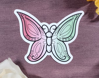 Könnte beinhalten: Ein Aufkleber mit einem Schmetterling mit rosa und grünen Flügeln. Der Schmetterling hat einen schwarzen Umriss und einen weißen Körper.