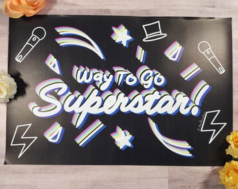 Könnte beinhalten: Schwarz-weißes Poster mit dem Text "Way to go Superstar!" in einer bunten Retro-Schrift. Das Poster ist mit Sternen, Blitzen und Mikrofonen verziert.