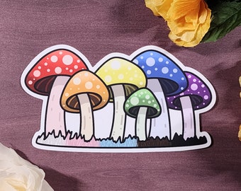 Könnte beinhalten: Ein Aufkleber mit einer Gruppe von sechs Cartoon-Pilzen in einem Regenbogen-Farbschema. Die Pilze sind in einer Reihe angeordnet, wobei der größte Pilz hinten und der kleinste Pilz vorne ist. Die Pilze sind alle weiß mit Punkten in ihren jeweiligen Farben.