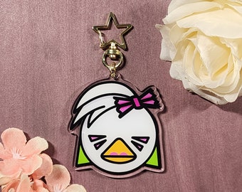 Könnte beinhalten: Weißer und grüner Cartoon-Enten-Schlüsselanhänger mit einer rosa Schleife. Der Schlüsselanhänger hat einen goldenen sternförmigen Drehverschluss.