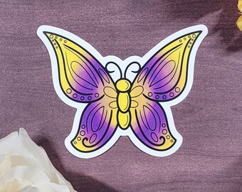 Könnte beinhalten: Ein gelber und lilafarbener Schmetterlingsaufkleber mit weißem Rand. Der Schmetterling hat ein detailliertes Design mit schwarzen Linien und kleinen Kreisen.