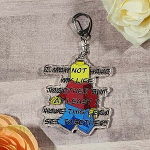 May include: A clear acrylic keychain featuring a Lego minifigure with the text "I may not have my life together but at least I have this Lego set together!"