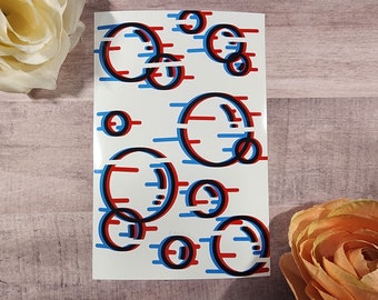 Könnte beinhalten: Ein weißer Aufkleber mit einem sich wiederholenden Muster aus schwarzen, roten und blauen Kreisen. Die Kreise sind übereinander gelegt und scheinen sich in 3D zu bewegen.