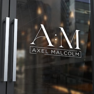 Könnte beinhalten: Ein Schaufenster mit einem weißen Logo, das "A:M AXEL MALCOLM" lautet.