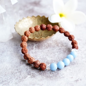 Peut inclure: Un bracelet en perles brunes et bleues avec un bol en or en arrière-plan. Le bracelet est composé de petites perles brunes et de plus grosses perles bleues.