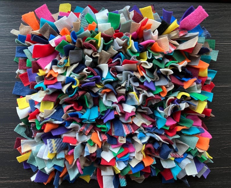 May include: A colorful, multi-textured dog toy made from various fabrics. The toy is a square shape and is made of many different colors and textures of fabric.