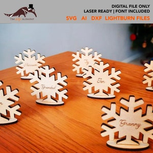 Könnte beinhalten: Holz-Schneeflocken-Tischkarten mit Namen wie "Harrison", "Jen", "Grandad" und "Granny". Die Karten stehen auf einer Holzoberfläche. Der Text "DIGITAL FILE ONLY" und "LASER READY | FONT INCLUDED" ist ebenfalls zu sehen.