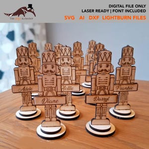 May include: Laser-cut wooden nutcracker figurines with nameplates. The figurines have detailed crowns, moustaches, and uniforms. Each stands on a circular base. The image includes the text "DIGITAL FILE ONLY" and "LASER READY | FONT INCLUDED".