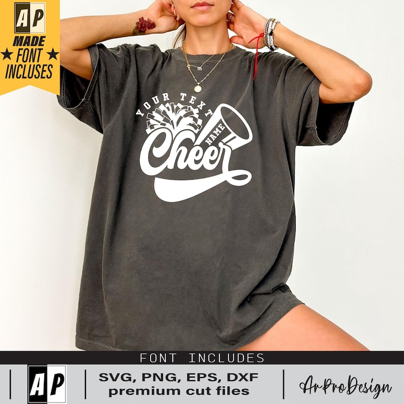 Peut inclure: Un t-shirt gris avec un motif blanc de pompon de pom-pom et de m&eacute;gaphone de cheerleader avec le texte "Your Text Name Cheer".