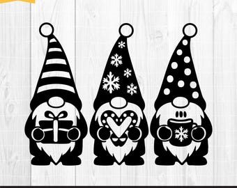 May include: Three black and white gnome cut files. Each gnome wears a tall hat with different patterns: stripes, snowflakes, and polka dots. The gnomes hold a gift, a heart, and a mug. The image includes the text "SVG, PNG, EPS, DXF premium cut files".