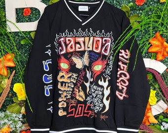 May include: Black long-sleeve sweatshirt with a colorful graphic print featuring flames, a butterfly, and the text "Jajuda", "505", "Power", "Hidden", "Knowledge", "Wisdom", "Strength", and "Never How Sing You Are Until Beauty Is Strong Only One".