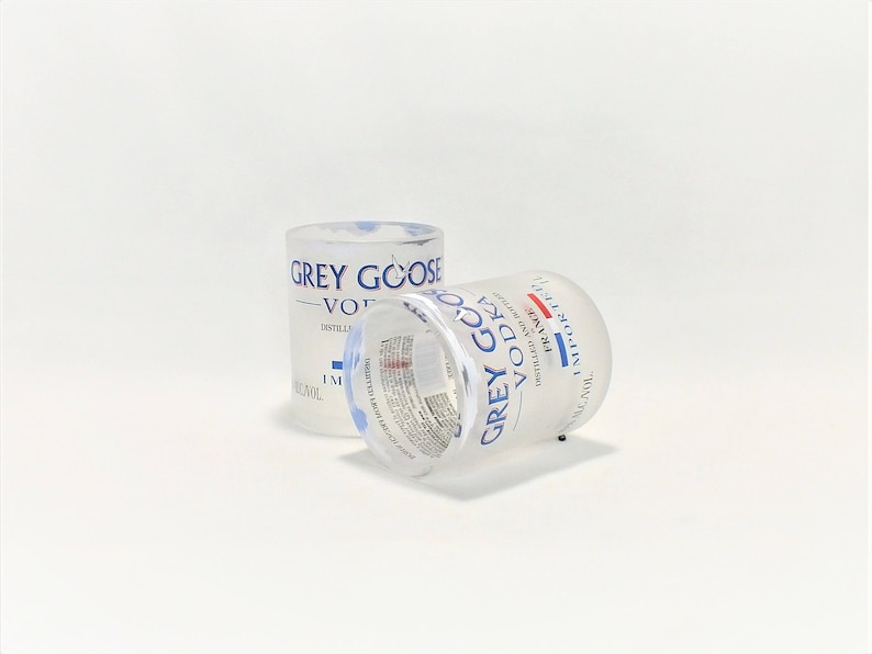 K&ouml;nnte beinhalten: Zwei klare Glas-Shotgl&auml;ser mit der Aufschrift "Grey Goose Vodka". Die Gl&auml;ser sind teilweise mit einer klaren Fl&uuml;ssigkeit gef&uuml;llt.