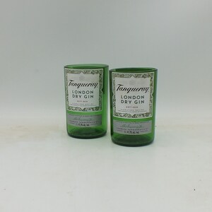May include: Two green glass bottles of Tanqueray London Dry Gin. The bottles are empty and have a white label with black text.