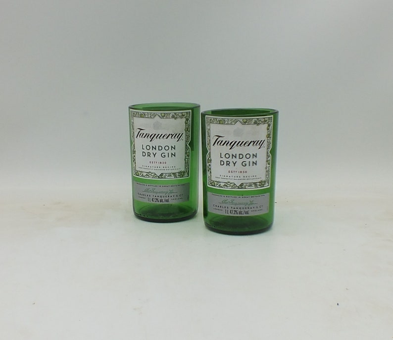 May include: Two green glass bottles of Tanqueray London Dry Gin. The bottles are empty and have a white label with black text.