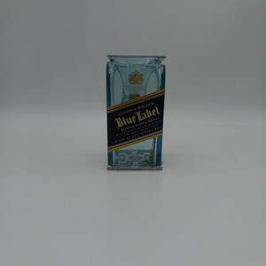 May include: A blue glass bottle with a Johnnie Walker Blue Label blended Scotch whisky label. The bottle is empty and has a clear glass stopper.