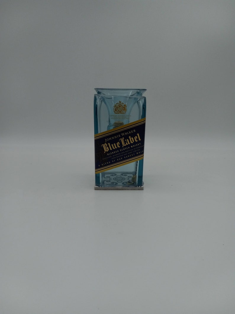 May include: A blue glass bottle with a Johnnie Walker Blue Label blended Scotch whisky label. The bottle is empty and has a clear glass stopper.