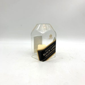 May include: A clear glass bottle with a label that reads "JOHNNIE WALKER BLACK LABEL Blended Scotch Whisky DISTILLED, BLENDED AND BOTTLED IN SCOTLAND"