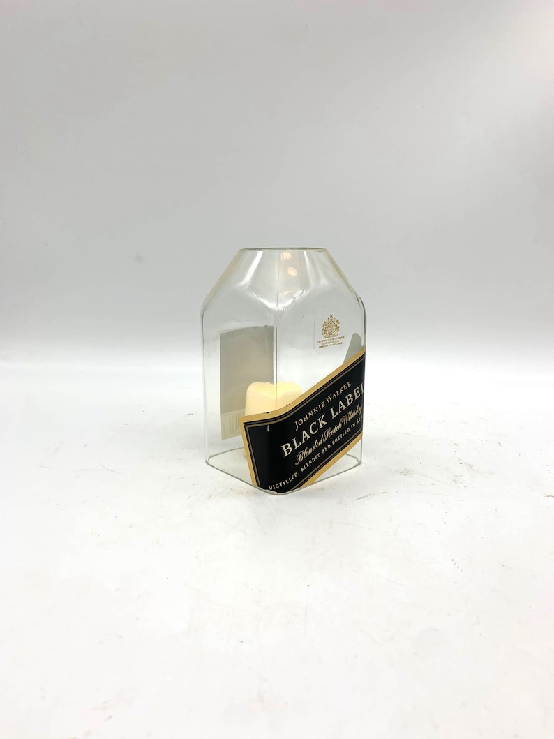 May include: A clear glass bottle with a label that reads "JOHNNIE WALKER BLACK LABEL Blended Scotch Whisky DISTILLED, BLENDED AND BOTTLED IN SCOTLAND"