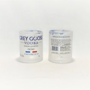 K&ouml;nnte beinhalten: Zwei klare Schnapsgl&auml;ser aus Glas mit mattierter Oberfl&auml;che. Die Vorderseite des Glases zeigt das Grey Goose Vodka-Logo mit dem Text "Grey Goose Vodka", "Destilliert und abgef&uuml;llt in Frankreich" und "Importiert". Die R&uuml;ckseite des Glases zeigt den Text "Destilliert aus franz&ouml;sischem Weizen" und einen Barcode.
