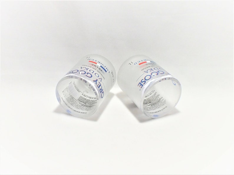 K&ouml;nnte beinhalten: Zwei klare Glas-Shotgl&auml;ser mit der Aufschrift "GREY GOOSE VODKA" auf der Seite. Die Gl&auml;ser sind leer und stehen auf einer wei&szlig;en Oberfl&auml;che.