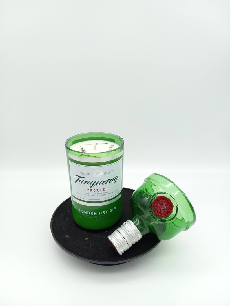 K&ouml;nnte beinhalten: Ein gr&uuml;nes Glas-Kerzengef&auml;&szlig; mit einer wei&szlig;en Kerze darin. Das Gef&auml;&szlig; ist mit "Tanqueray Imported London Dry Gin" beschriftet.
