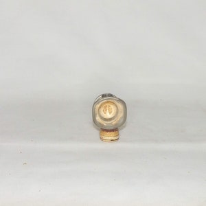 May include: A clear glass bottle with a cork stopper. The bottle has a square shape and a textured surface. The cork stopper has a brown and white design.