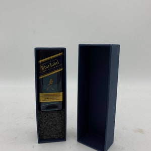 May include: A miniature bottle of Johnnie Walker Blue Label Blended Scotch Whisky in a blue box. The bottle is clear and has a gold label with the Johnnie Walker logo and the words "Blue Label" in gold lettering.