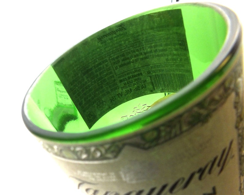May include: An empty green glass bottle with a white label that reads "Tanqueray" and features a barcode. The label is partially visible.