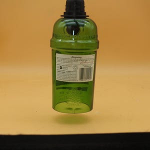 K&ouml;nnte beinhalten: Eine gr&uuml;ne Glasflasche mit schwarzem Verschluss. Die Flasche hat ein Etikett mit dem Text "Tanqueray" und weiteren Informationen zum Produkt. Die Flasche h&auml;ngt am Verschluss.