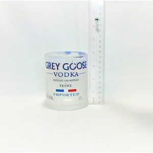 K&ouml;nnte beinhalten: Eine gefrostete Glasflasche Grey Goose Wodka. Die Flasche ist 1 Liter gro&szlig; und tr&auml;gt die Aufschrift "Destilliert und abgef&uuml;llt in Frankreich" und "Importiert".