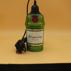 K&ouml;nnte beinhalten: Eine gr&uuml;ne Glasflasche mit einem schwarzen Kabel und Stecker. Die Flasche tr&auml;gt ein Etikett mit der Aufschrift "Tanqueray Imported London Dry Gin".