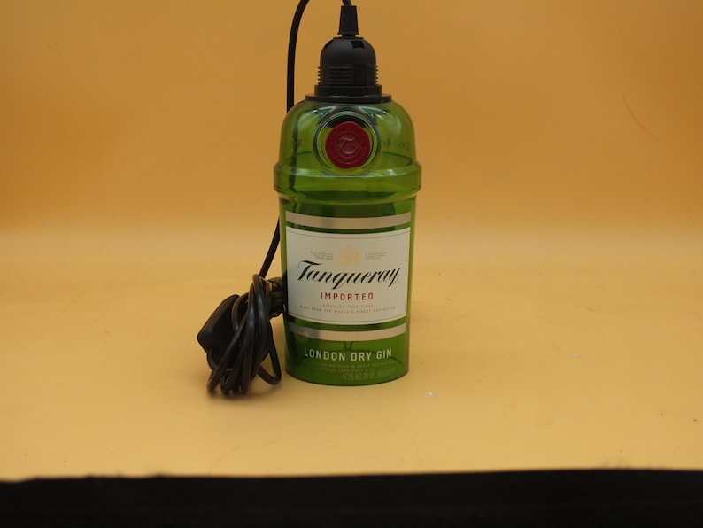 K&ouml;nnte beinhalten: Eine gr&uuml;ne Glasflasche mit einem schwarzen Kabel und Stecker. Die Flasche tr&auml;gt ein Etikett mit der Aufschrift "Tanqueray Imported London Dry Gin".