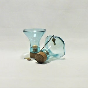 May include: Two clear blue glass bottles with cork stoppers and a string attached to one of the bottles.
