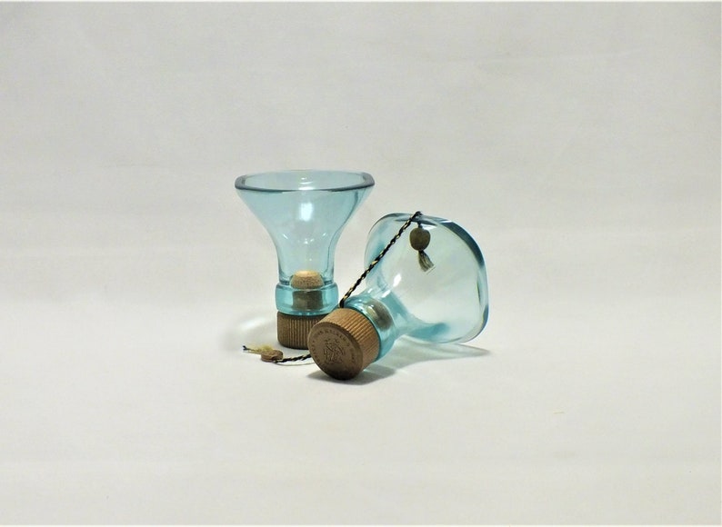 May include: Two clear blue glass bottles with cork stoppers and a string attached to one of the bottles.