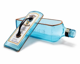 May include: A repurposed Bombay Sapphire gin bottle transformed into a serving tray. The light blue glass bottle features a black handle and a copper-colored trim. The label is still visible, with the text "Bombay Sapphire London Dry Gin".
