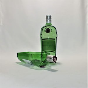 Op de afbeelding: Twee groene glazen flessen, &eacute;&eacute;n rechtop en &eacute;&eacute;n liggend. De rechtopstaande fles heeft een zilveren dop en een etiket met de tekst "Gordon's London Dry Gin". De liggende fles heeft een rode dop.