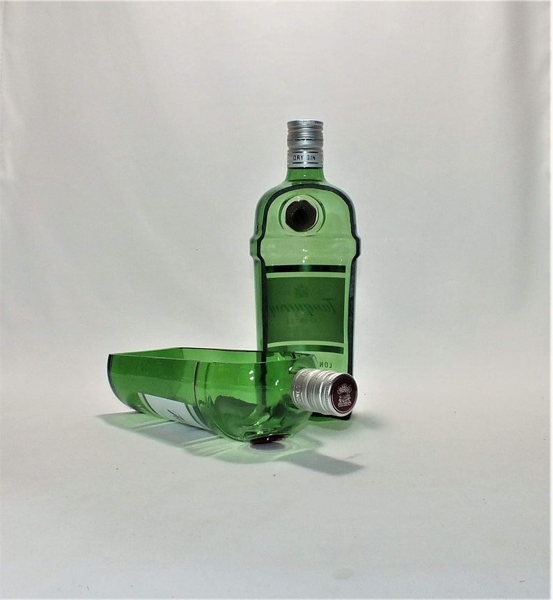 Op de afbeelding: Twee groene glazen flessen, &eacute;&eacute;n rechtop en &eacute;&eacute;n liggend. De rechtopstaande fles heeft een zilveren dop en een etiket met de tekst "Gordon's London Dry Gin". De liggende fles heeft een rode dop.