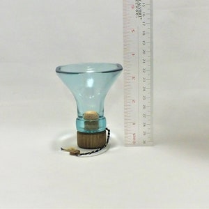May include: A light blue glass funnel with a cork stopper and a wooden base. The funnel is approximately 10 cm tall.
