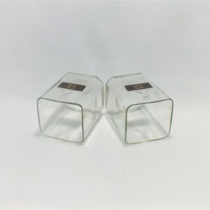 May include: Two clear glass square tumblers with a brown label that says "Old Forester" on each.